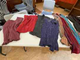 Several handwoven crimp cloth garments laid out on a table for viewing.